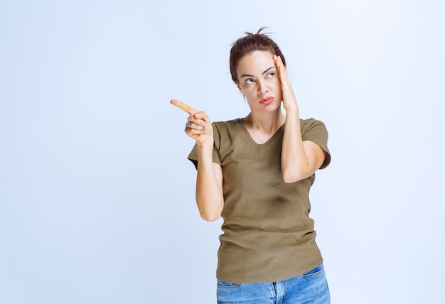 Mujer joven en camisa verde apuntando a algo