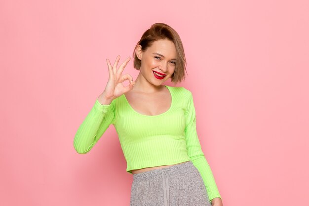 Mujer joven en camisa verde y falda gris posando con una sonrisa