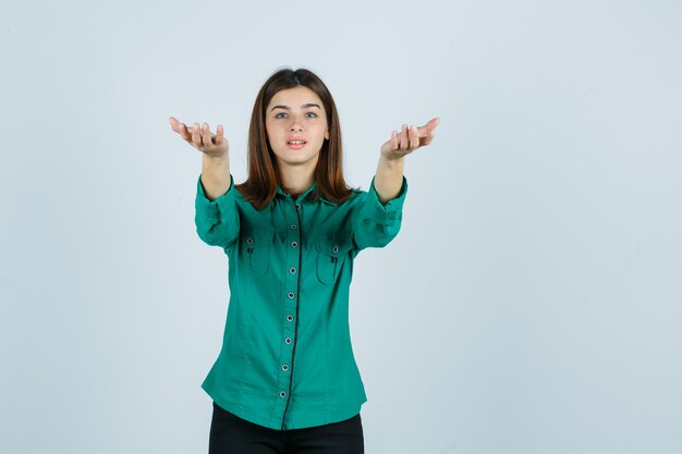 Foto gratuita mujer joven en camisa verde invitando a venir y mirando emocionado, vista frontal.