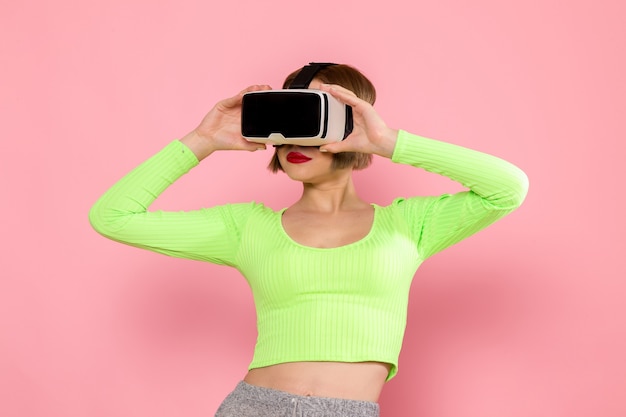 Mujer joven con camisa verde y pantalón gris probando un juego de realidad virtual