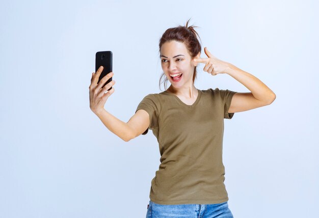 Mujer joven en camisa verde tomando su selfie y parece motivada