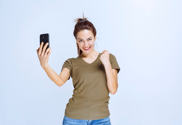 Mujer joven en camisa verde tomando su selfie y parece motivada