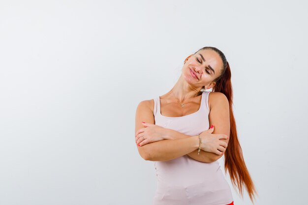 Foto gratuita mujer joven en camiseta abrazándose a sí misma y luciendo linda, vista frontal.