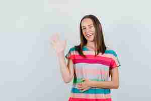 Foto gratuita mujer joven en camiseta agitando la mano y guiñando un ojo, vista frontal.