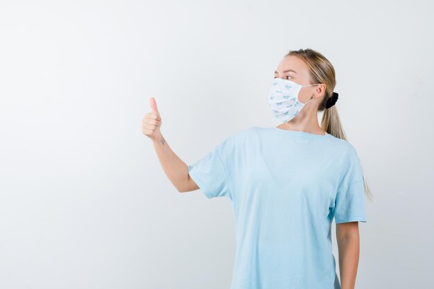 Mujer joven en una camiseta azul con una máscara médica