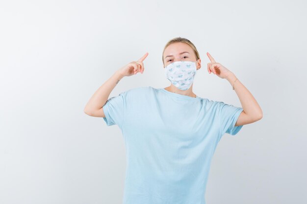 Mujer joven en una camiseta azul con una máscara médica