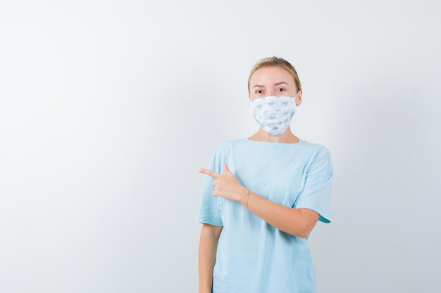 Mujer joven en una camiseta azul con una máscara médica