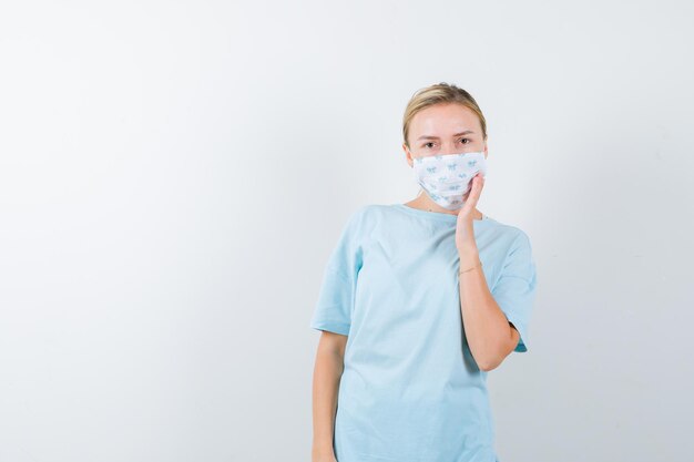 Mujer joven en una camiseta azul con una máscara médica