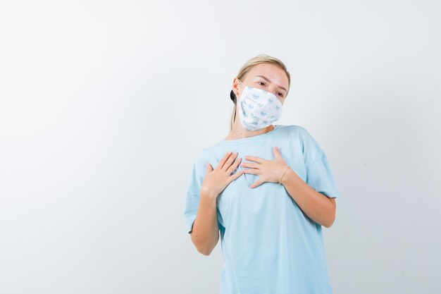 Mujer joven en una camiseta azul con una máscara médica