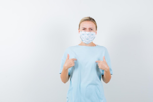 Mujer joven en una camiseta azul con una máscara médica