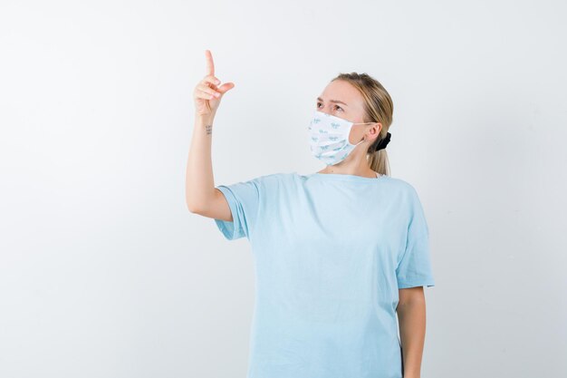 Mujer joven en una camiseta azul con una máscara médica