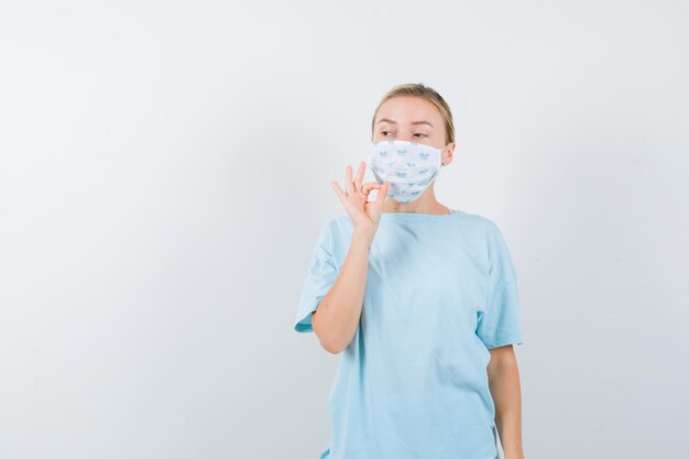 Mujer joven en una camiseta azul con una máscara médica