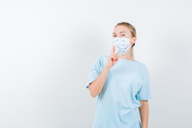 Mujer joven en una camiseta azul con una máscara médica