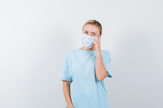 Mujer joven en una camiseta azul con una máscara médica