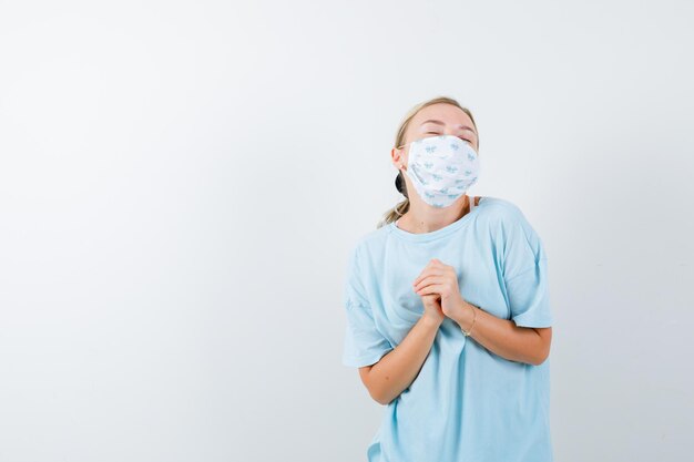 Mujer joven en una camiseta azul con una máscara médica