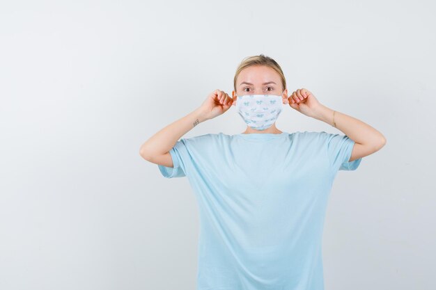 Mujer joven en una camiseta azul con una máscara médica