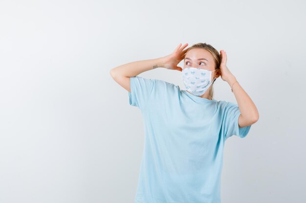 Mujer joven en una camiseta azul con una máscara médica