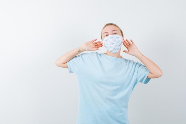 Mujer joven en una camiseta azul con una máscara médica