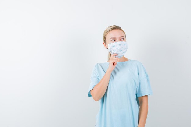 Mujer joven en una camiseta azul con una máscara médica