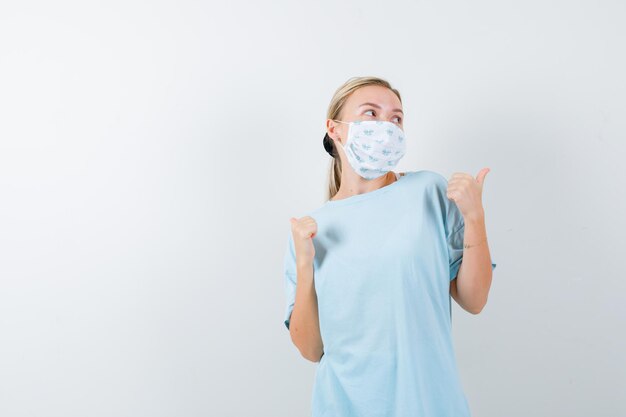 Mujer joven en una camiseta azul con una máscara médica