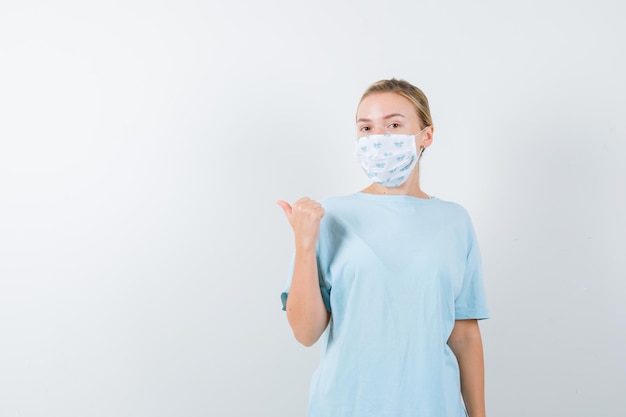 Mujer joven en una camiseta azul con una máscara médica