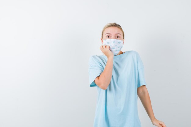 Mujer joven en una camiseta azul con una máscara médica