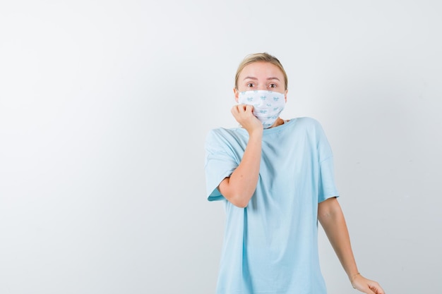 Mujer joven en una camiseta azul con una máscara médica