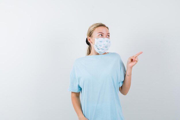 Mujer joven en una camiseta azul con una máscara médica