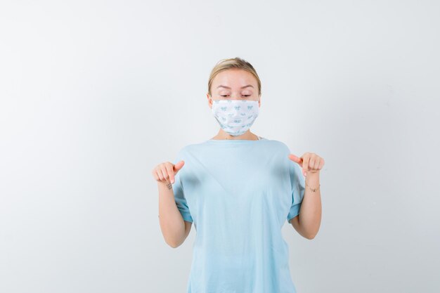 Mujer joven en una camiseta azul con una máscara médica