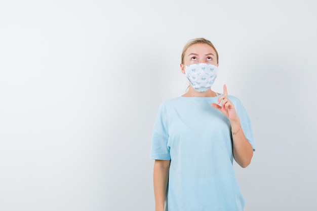 Foto gratuita mujer joven en una camiseta azul con una máscara médica