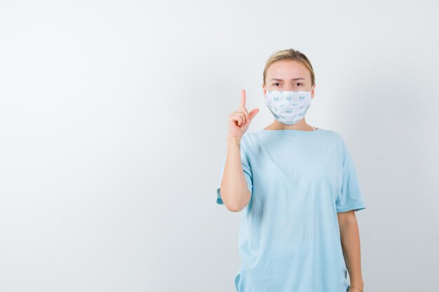 Mujer joven en una camiseta azul con una máscara médica