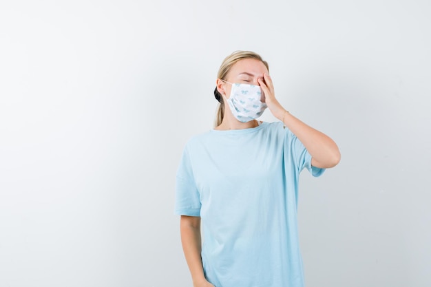 Mujer joven en una camiseta azul con una máscara médica