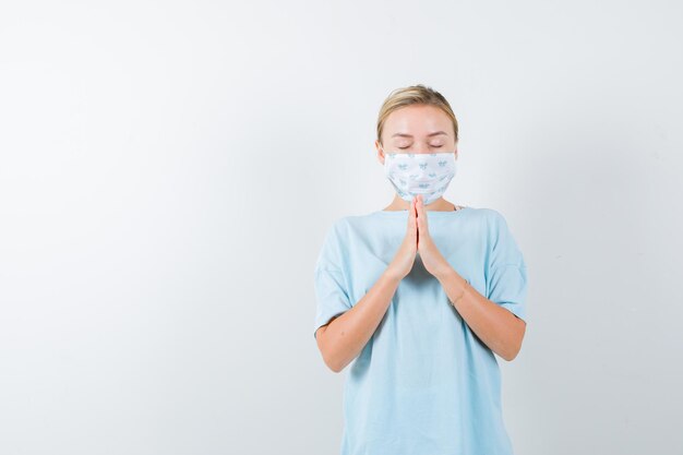 Mujer joven en una camiseta azul con una máscara médica