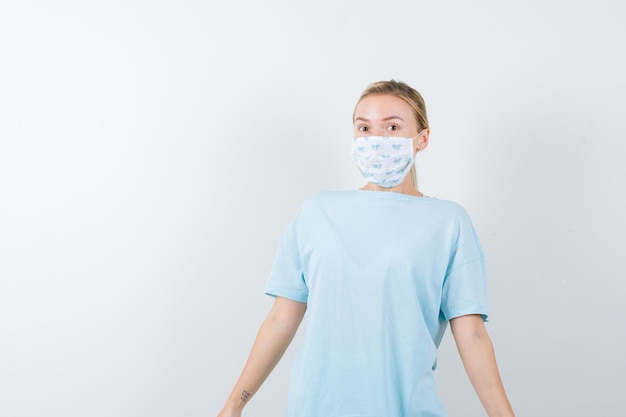 Mujer joven en una camiseta azul con una máscara médica