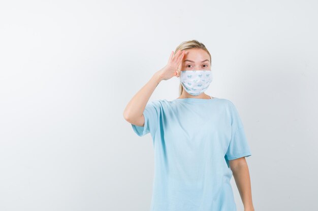 Mujer joven en una camiseta azul con una máscara médica