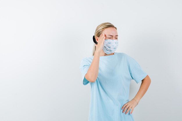 Mujer joven en una camiseta azul con una máscara médica