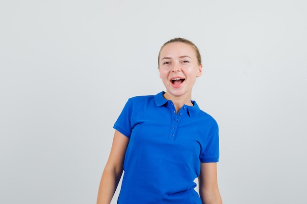 Mujer joven en camiseta azul mirando y mirando feliz