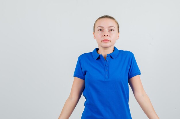 Mujer joven en camiseta azul mirando y mirando tranquilo