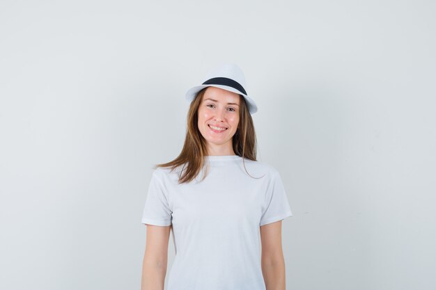 Mujer joven con camiseta blanca, sombrero y alegre.