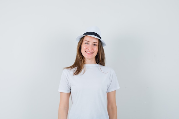 Mujer joven con camiseta blanca, sombrero y alegre.