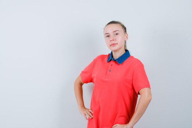 Mujer joven en camiseta cogidos de la mano en la cintura y mirando confiado