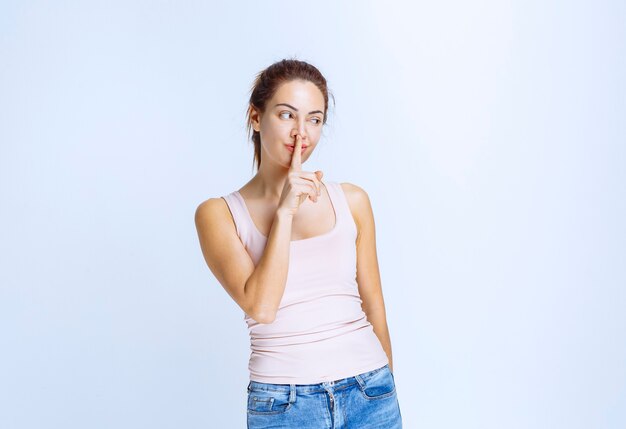 Mujer joven en camiseta deportiva pidiendo silencio