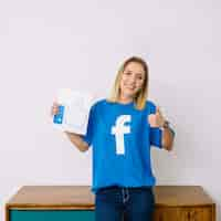 Foto gratuita mujer joven con camiseta de facebook sosteniendo como icono mostrando signo thumbup