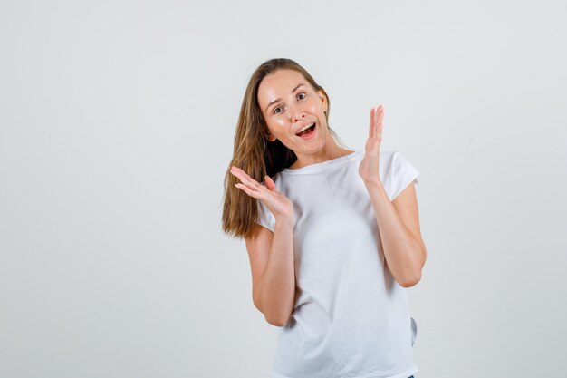 Mujer joven en camiseta gesticulando con las manos y mirando alegre