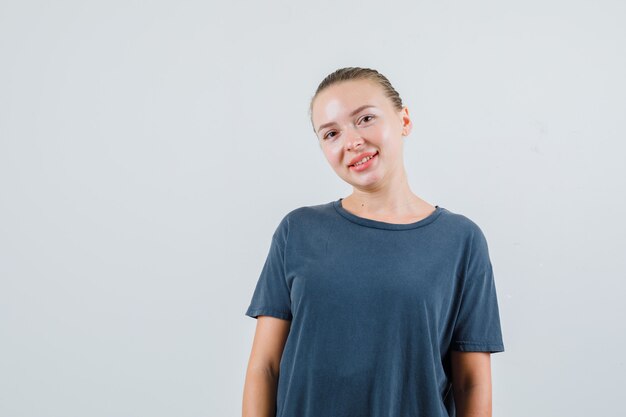 Mujer joven en camiseta gris mirando y mirando positivo