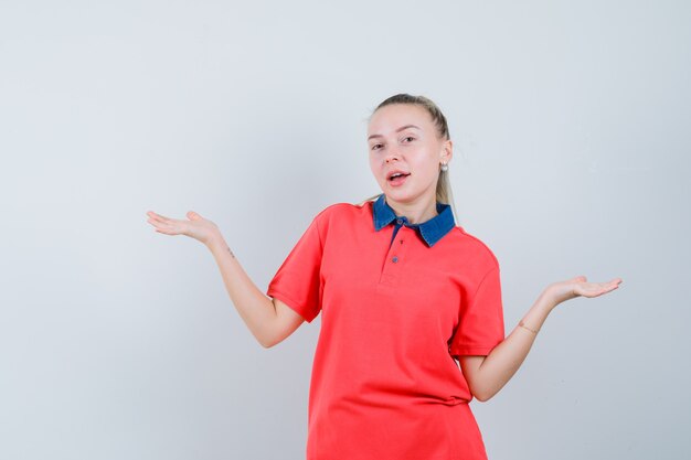 Mujer joven en camiseta haciendo gesto de escalas y mirando confiado