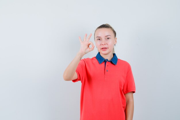 Mujer joven en camiseta mostrando gesto ok y mirando satisfecho