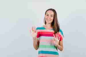 Foto gratuita mujer joven en camiseta mostrando gesto de rechazo cortésmente, vista frontal.