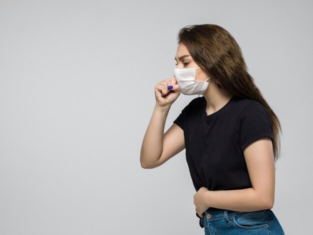 Mujer joven en camiseta negra y mascarilla estéril blanca