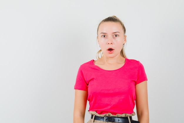 Foto gratuita mujer joven en camiseta y pantalón y mirando sorprendido